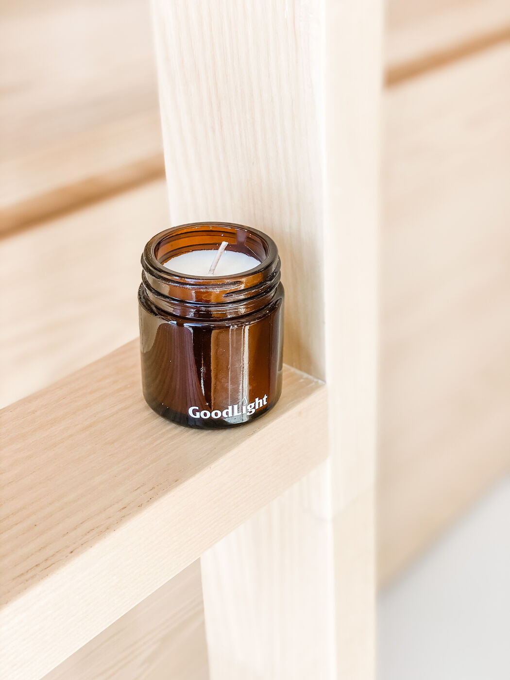 GoodLight amber glass candle on a wooden shelf