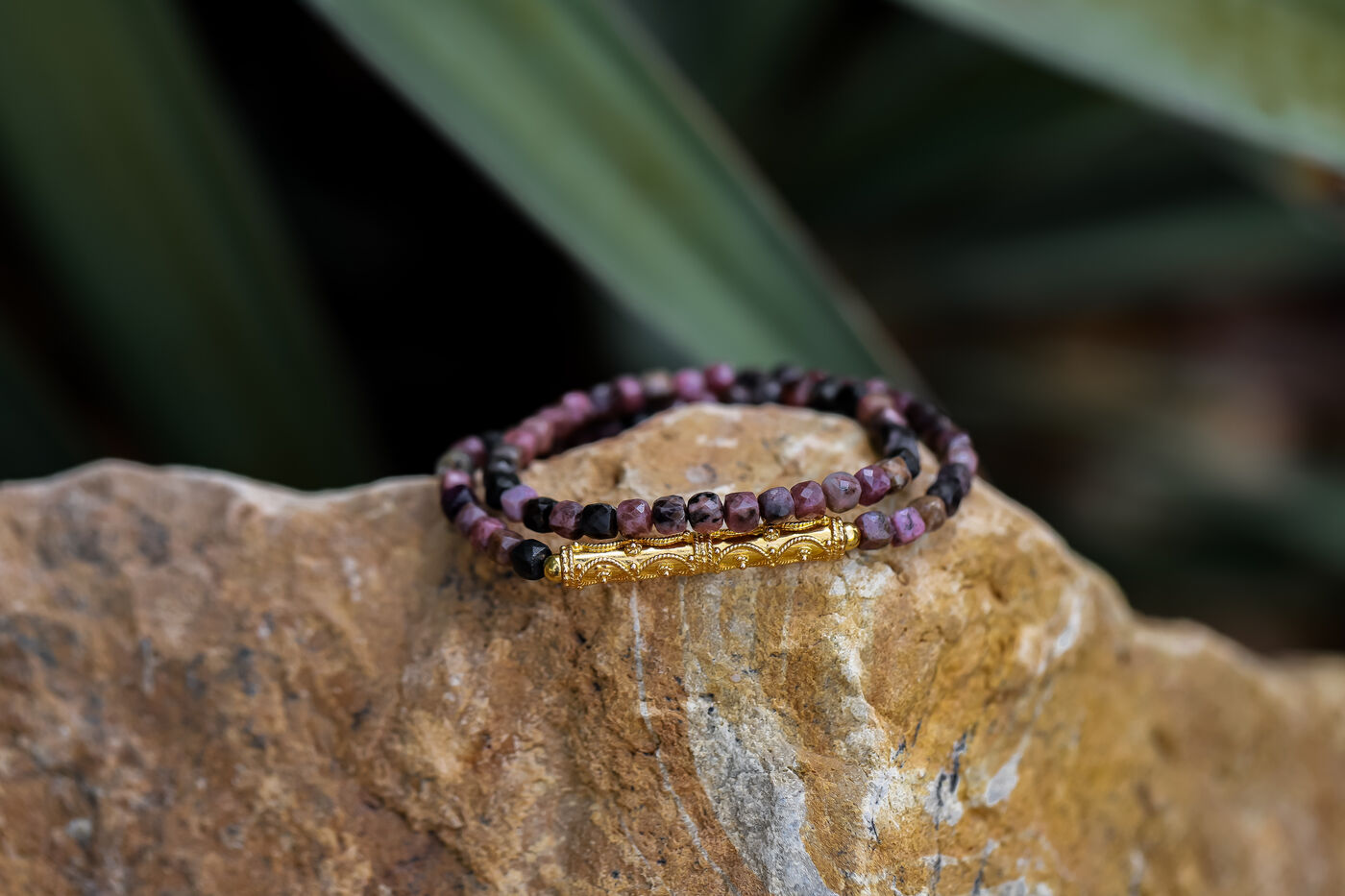 Beaded gemstone bracelet stack on a rock, gold clasp detail