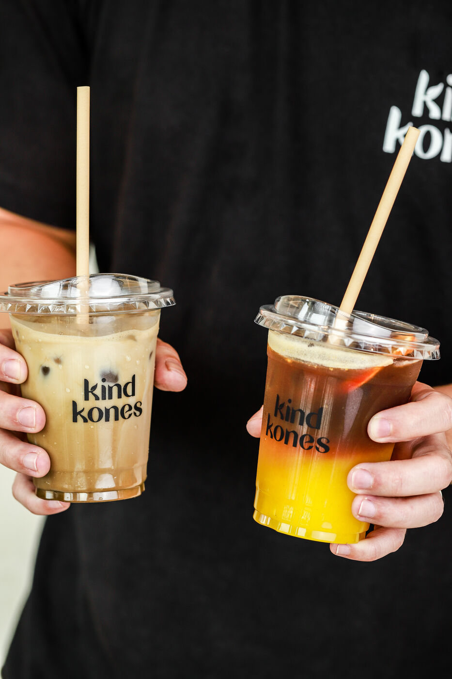 Man holding an iced latte and an iced orange drink from Kind Kones