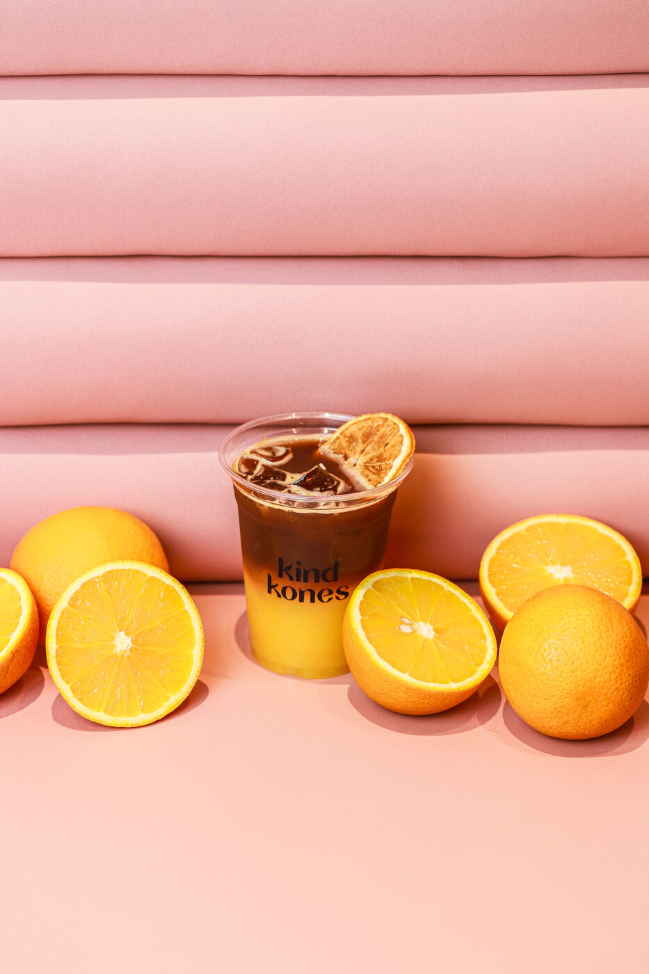 Kind Kones cold brew garnished with a dried orange slice, surrounded by fresh oranges