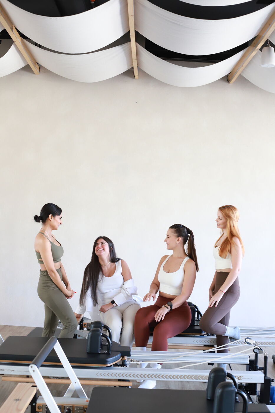 Four women chatting together in a pilates studio