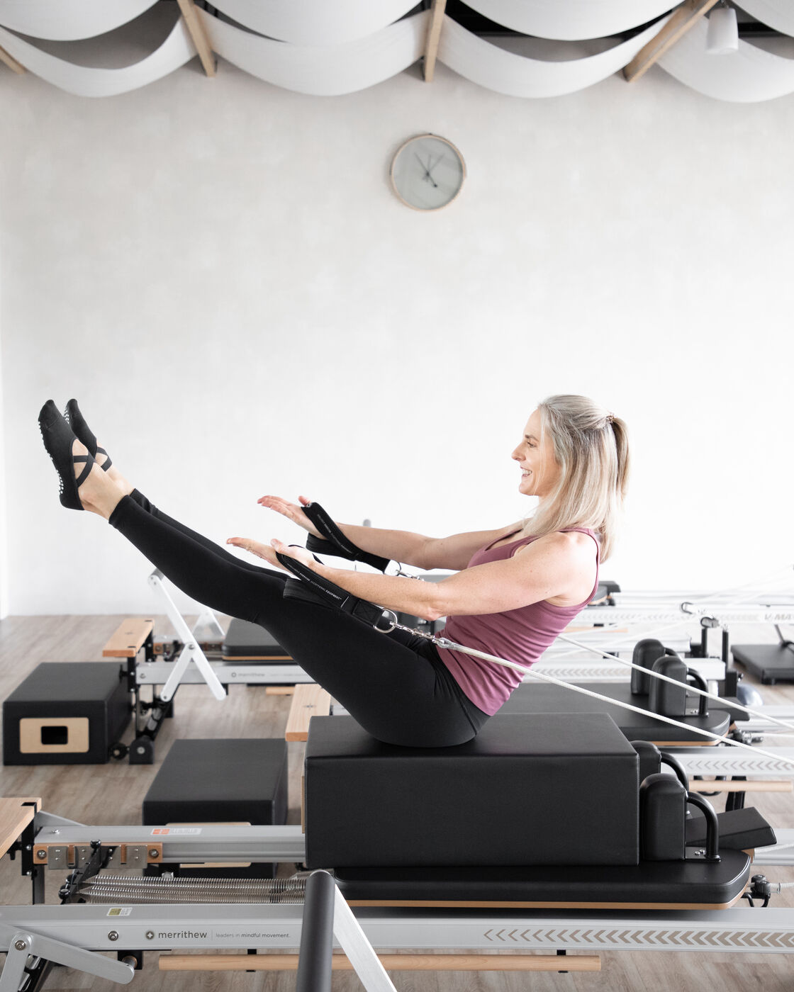 Woman smiling while using a pilates reformer machine