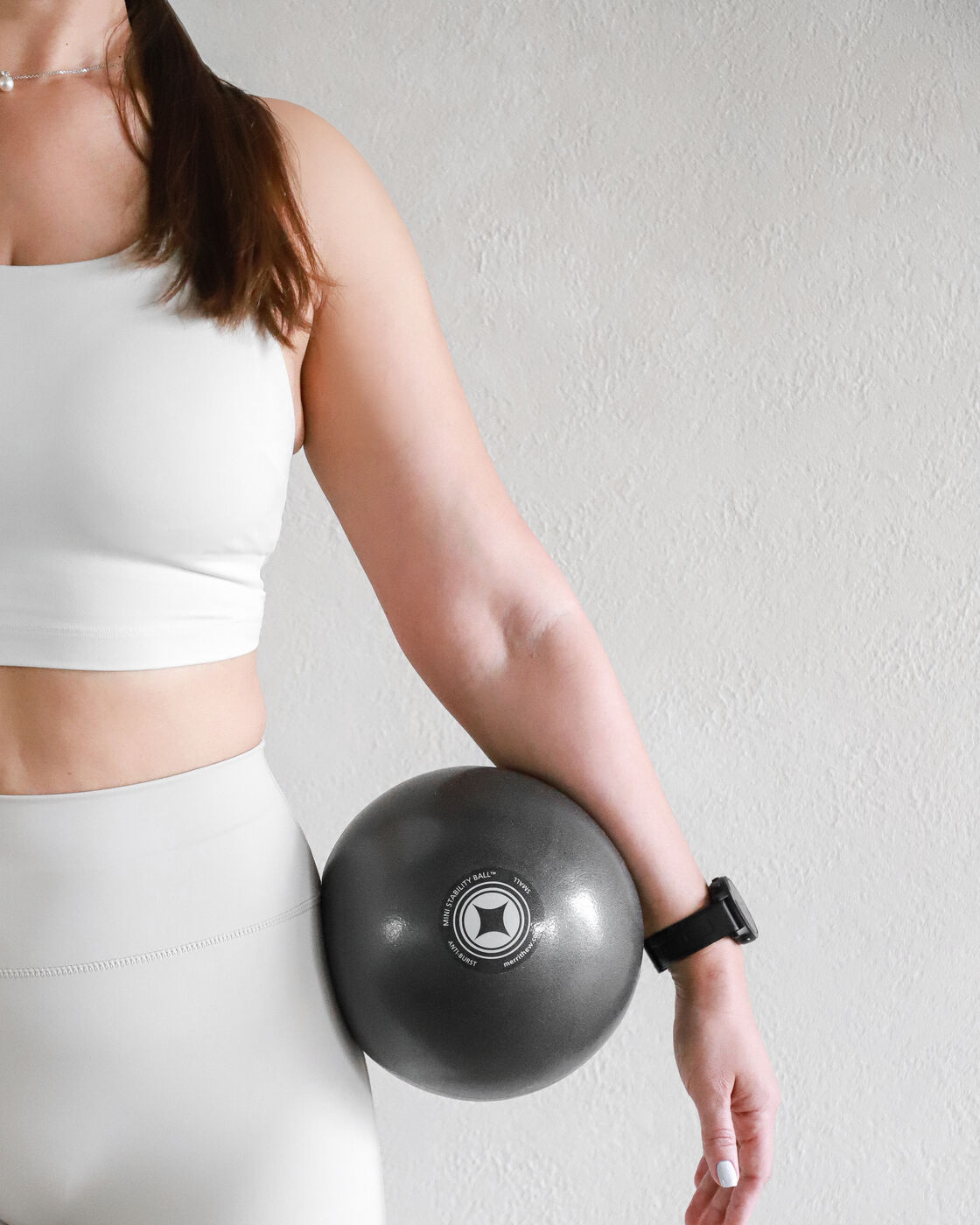 Woman holding a small pilates stability ball at her hip
