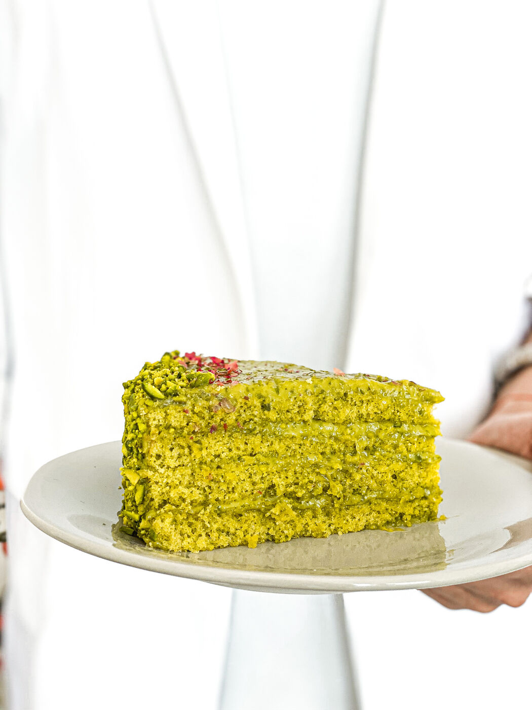Slice of pistachio layer cake on a white plate