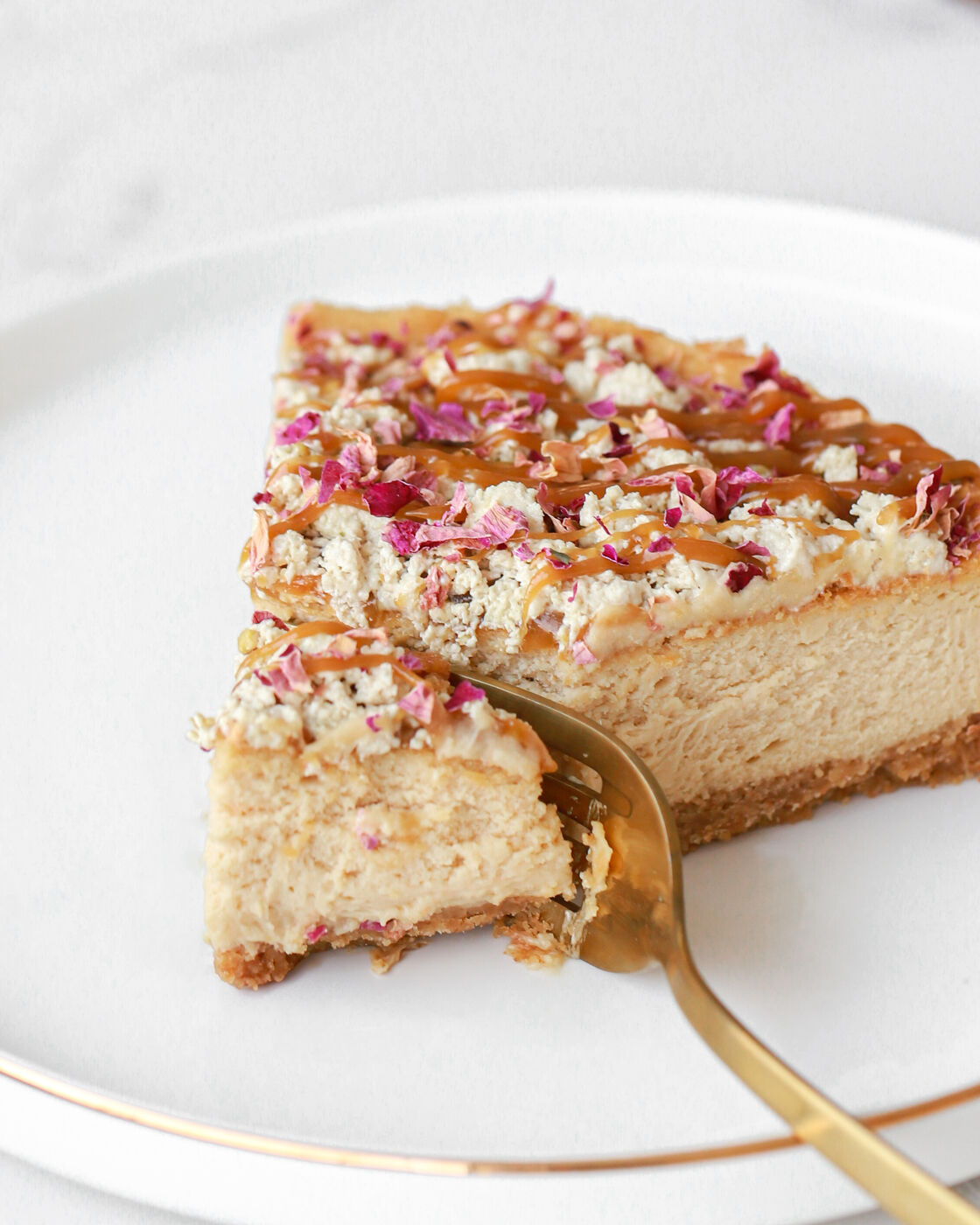 Slice of cheesecake topped with dried rose petals and caramel